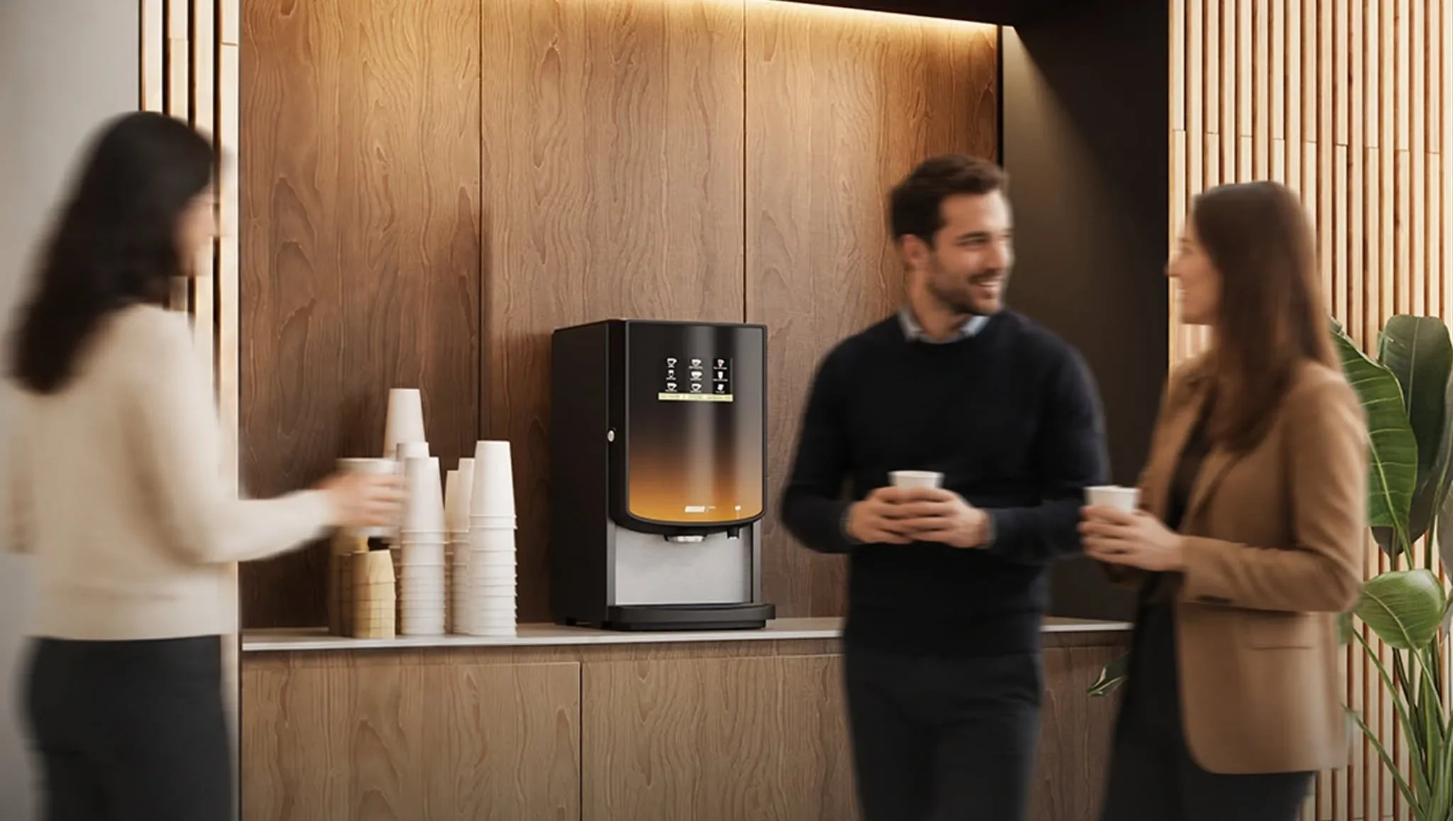 Kaffemaskine på disk med kopper og tre personer i samtale