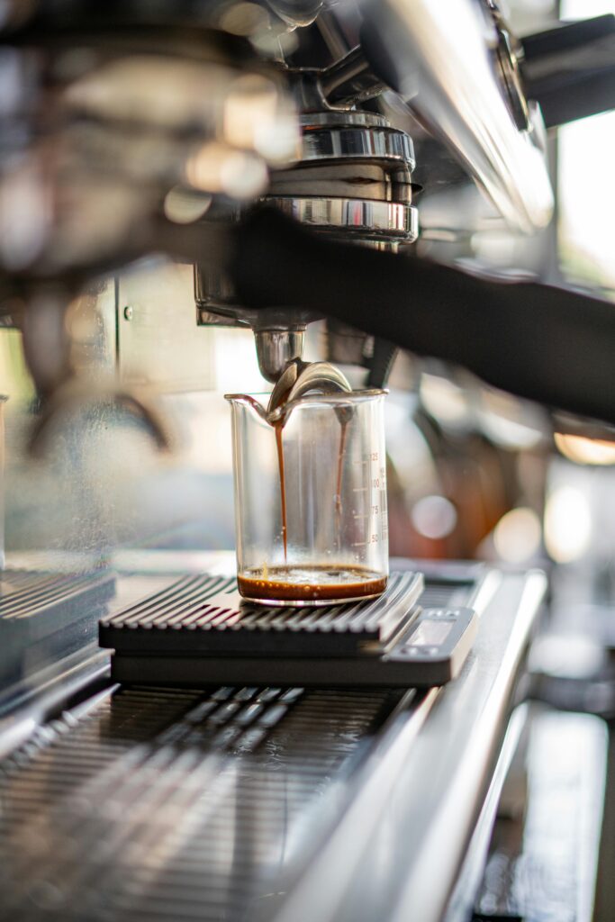 Espressomaskine brygger kaffe ned i et glas med hældetud