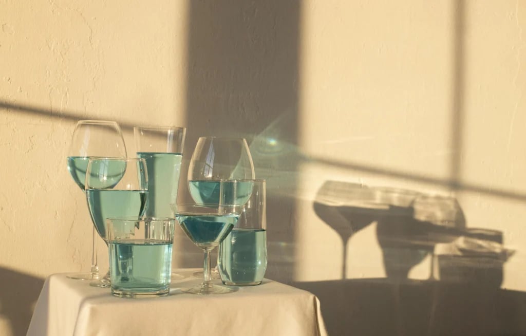Klare glas med blågrøn væske i sollys