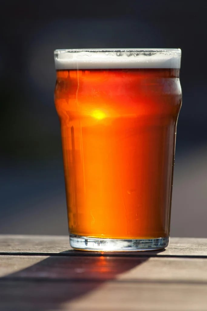 Glas med gyldent øl og hvidt skum på en mørk baggrund