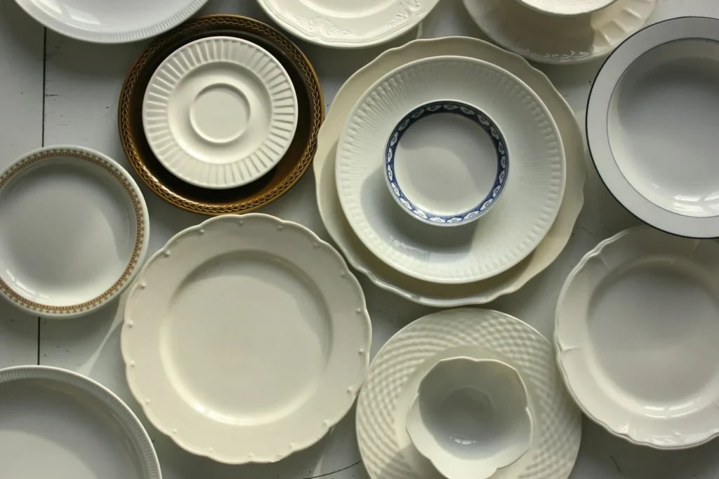 Lyse tallerkener, skåle og kopper med dekorative kanter set ovenfra
