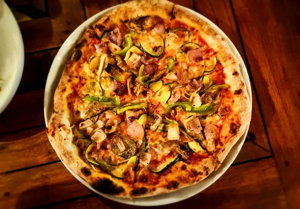 Pizza på en lys rund tallerken på et træbord