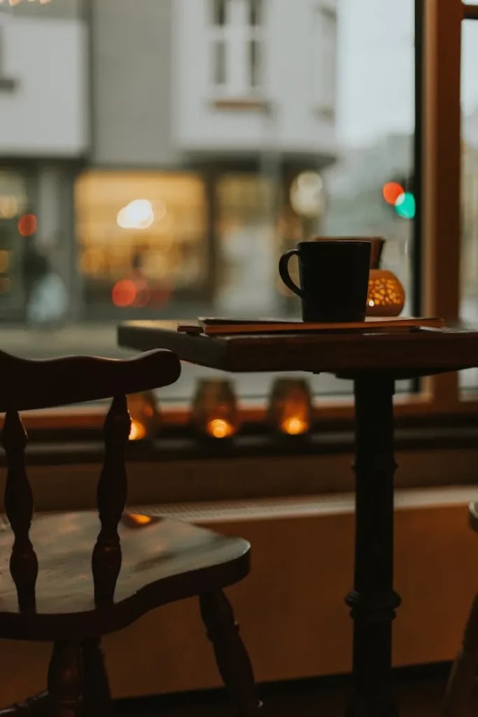 Sort kop på et cafébord ved et vindue
