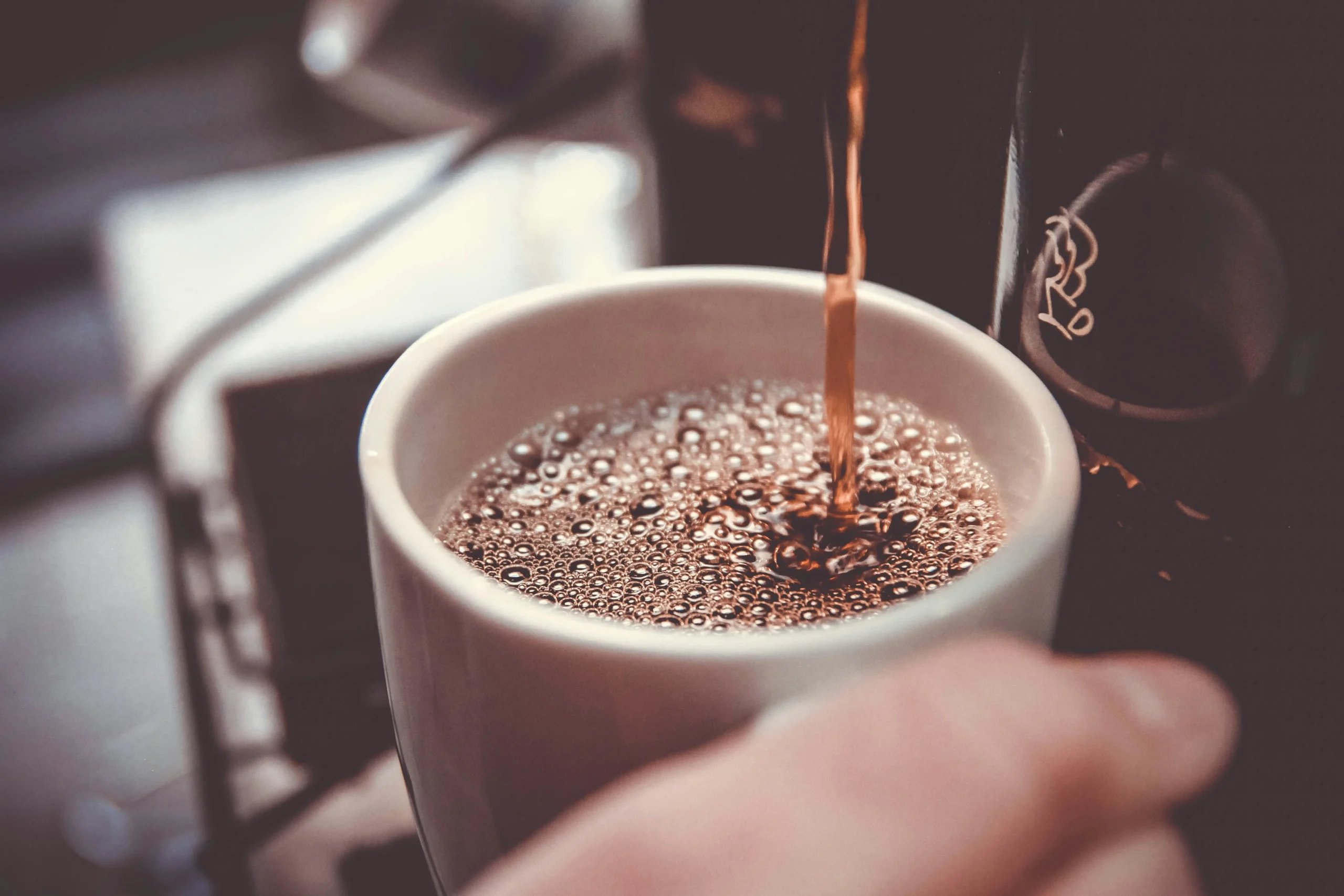 Kaffe hældes i en hvid kop
